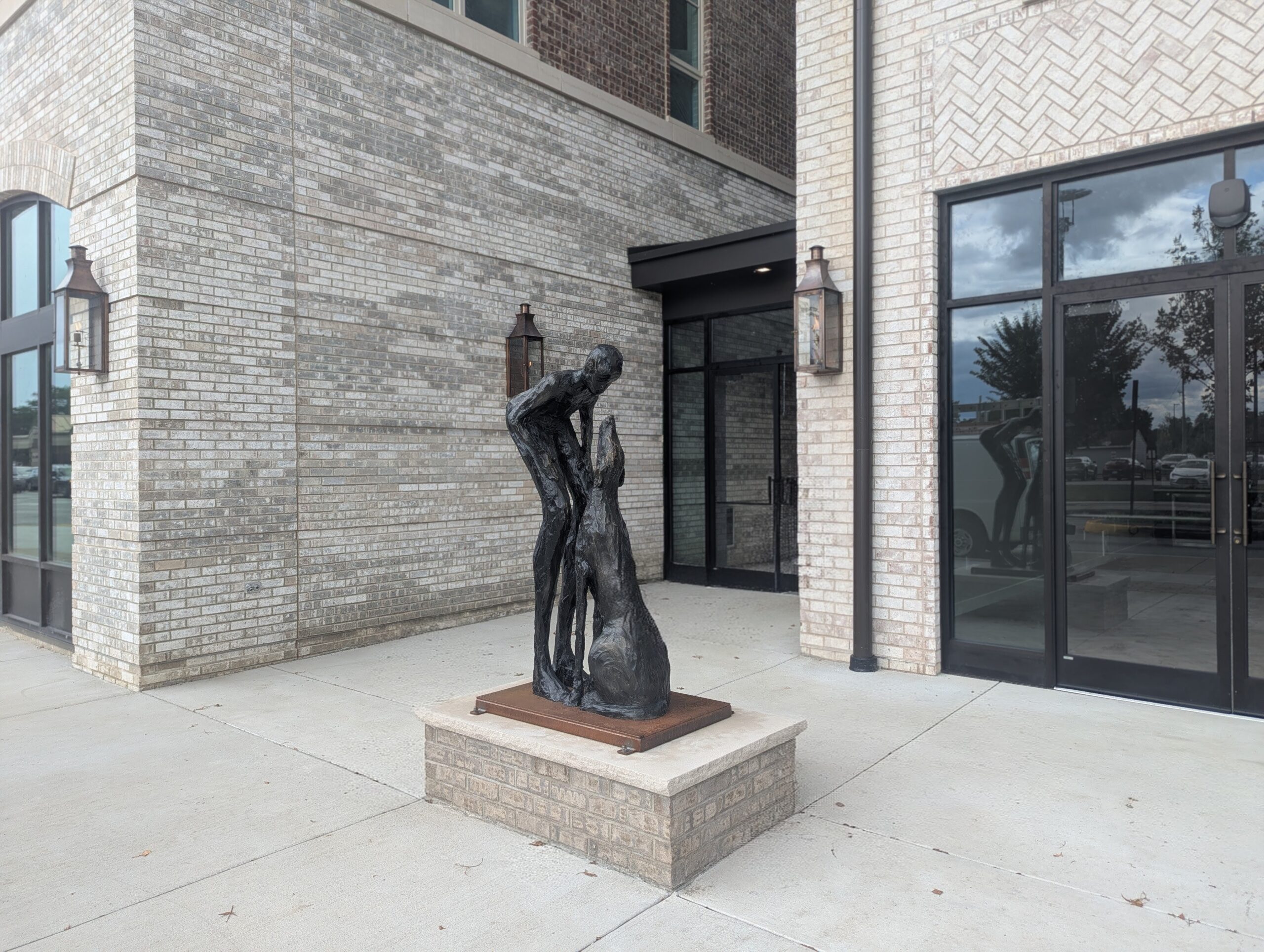 Public art sculpture “Who Rescued Who” by Lori Acott, showing a human figure with a dog.