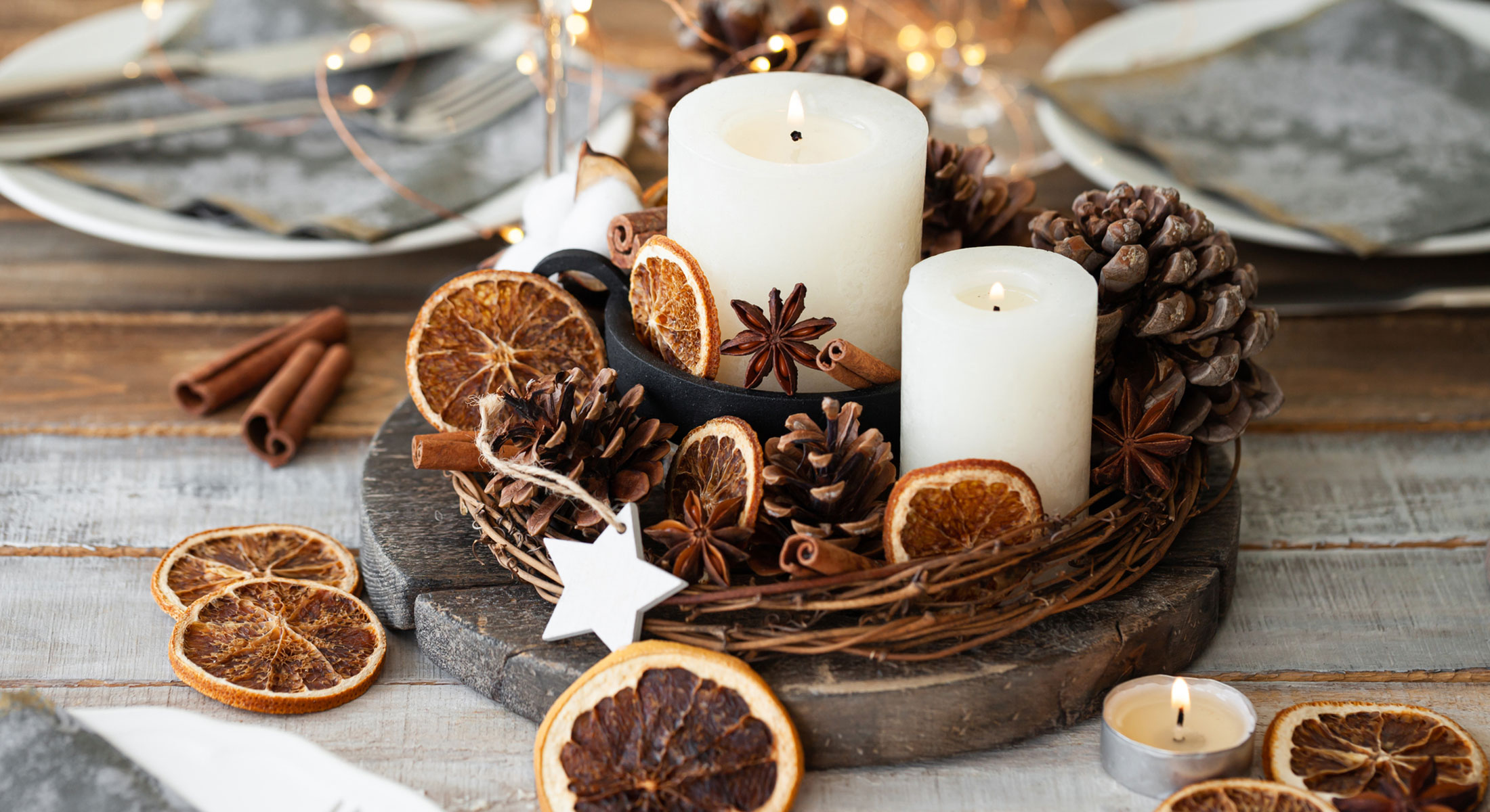 A tabletop holiday centerpiece made of candles and pinecones